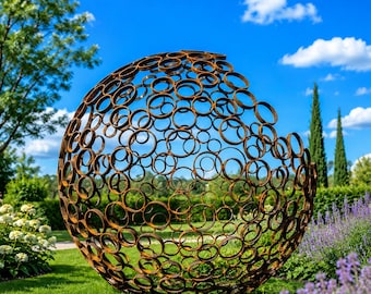 May include: A large, spherical outdoor sculpture made of interconnected rusty metal rings. The openwork design allows glimpses of the green lawn and blue sky. The sculpture is set in a garden with flowers and trees.