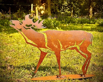 Puede incluir: Una escultura de metal oxidado de un ciervo de pie en un campo de hierba. El ciervo está mirando hacia la derecha y tiene la cabeza inclinada hacia arriba. La escultura está hecha de metal delgado y tiene un aspecto rústico y desgastado.