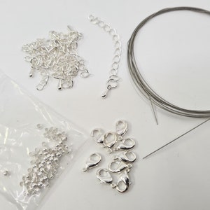 Peut inclure: Un ensemble de fournitures de fabrication de bijoux en argent comprenant une chaîne, des anneaux de saut, des fermoirs et du fil.