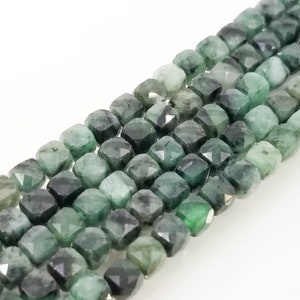 Può includere: Primo piano di fili di perline sfaccettate di pietra preziosa verde smeraldo. Le perline sono di forma quadrata con molteplici sfaccettature, creando un effetto scintillante. Ideale per la creazione di gioielli.