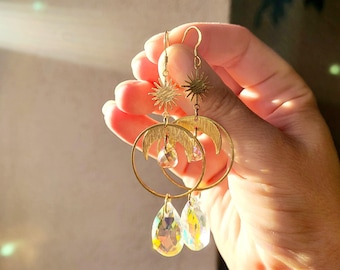 May include: Gold earrings with a crescent moon design, a starburst charm, and iridescent teardrop crystals.