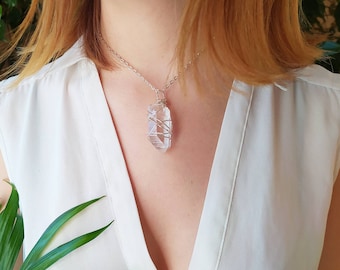 May include: A silver chain necklace with a clear quartz crystal pendant wrapped in silver wire.