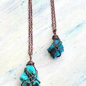 May include: Two copper wire wrapped turquoise stone pendants on copper chains. The stones are different sizes and shapes.