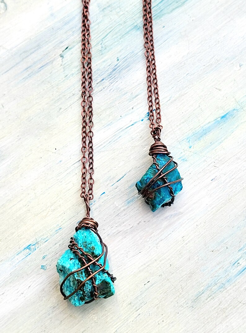 May include: Two copper wire wrapped turquoise stone pendants on copper chains. The stones are different sizes and shapes.
