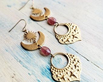 May include: Gold tone earrings with a crescent moon, sun, and star design. The earrings feature a pink gemstone bead.