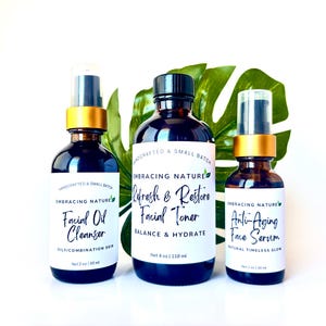 May include: Three amber glass bottles with gold lids and white labels. The labels read "Embracing Nature" and list the products as "Facial Oil Cleanser", "Refresh & Restore Facial Toner", and "Anti-Aging Face Serum".
