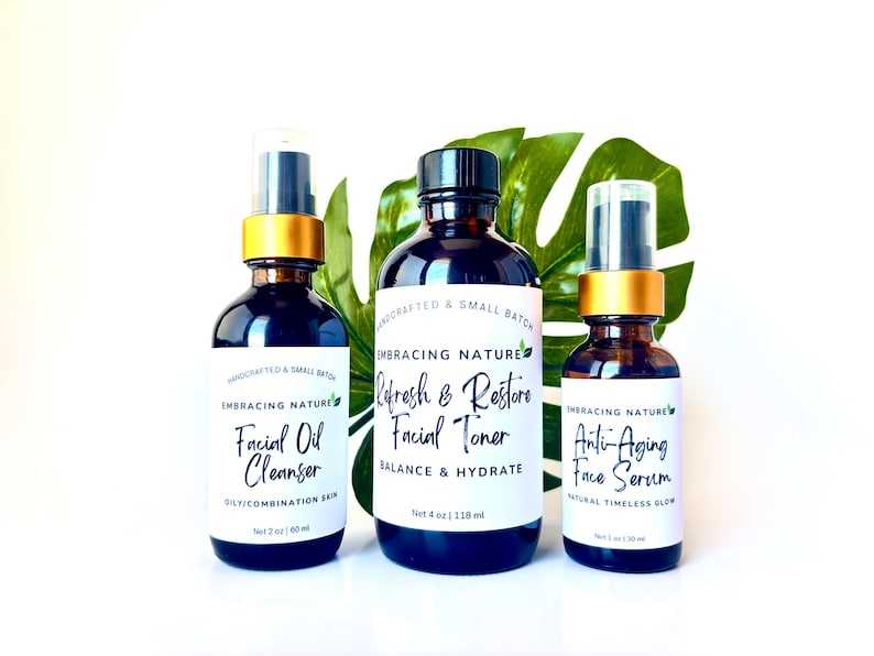 May include: Three amber glass bottles with gold lids and white labels. The labels read "Embracing Nature" and list the products as "Facial Oil Cleanser", "Refresh & Restore Facial Toner", and "Anti-Aging Face Serum".