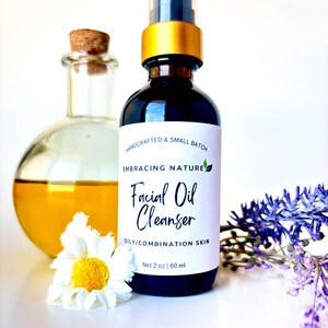 May include: A glass bottle with a gold cap and a white label that reads "HANDCRAFTED & SMALL BATCH EMBRACING NATURE Facial Oil Cleanser OILY/COMBINATION SKIN Net 2 oz | 60 ml".