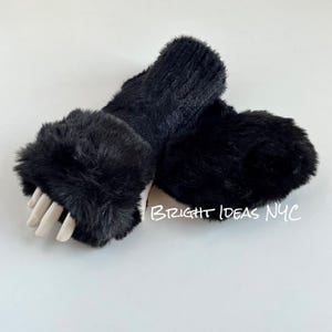 May include: A pair of black fingerless gloves with a faux fur cuff. The gloves are made of a soft, knitted fabric and have a warm, cozy feel.