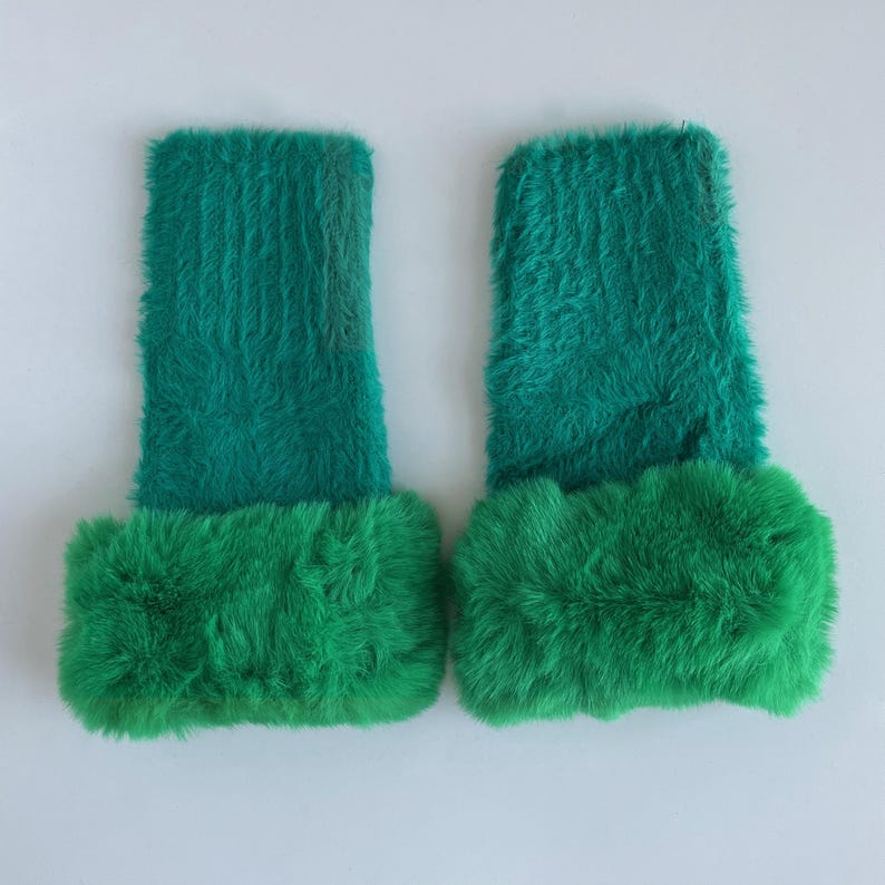 May include: A pair of green fuzzy wrist warmers with a fluffy trim. The wrist warmers are made of a soft, plush material.