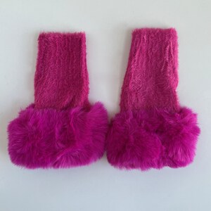 May include: A pair of pink fuzzy leg warmers with a fluffy pink trim.
