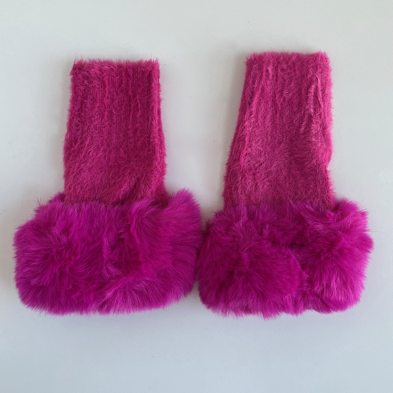 May include: A pair of pink fuzzy leg warmers with a fluffy pink trim.