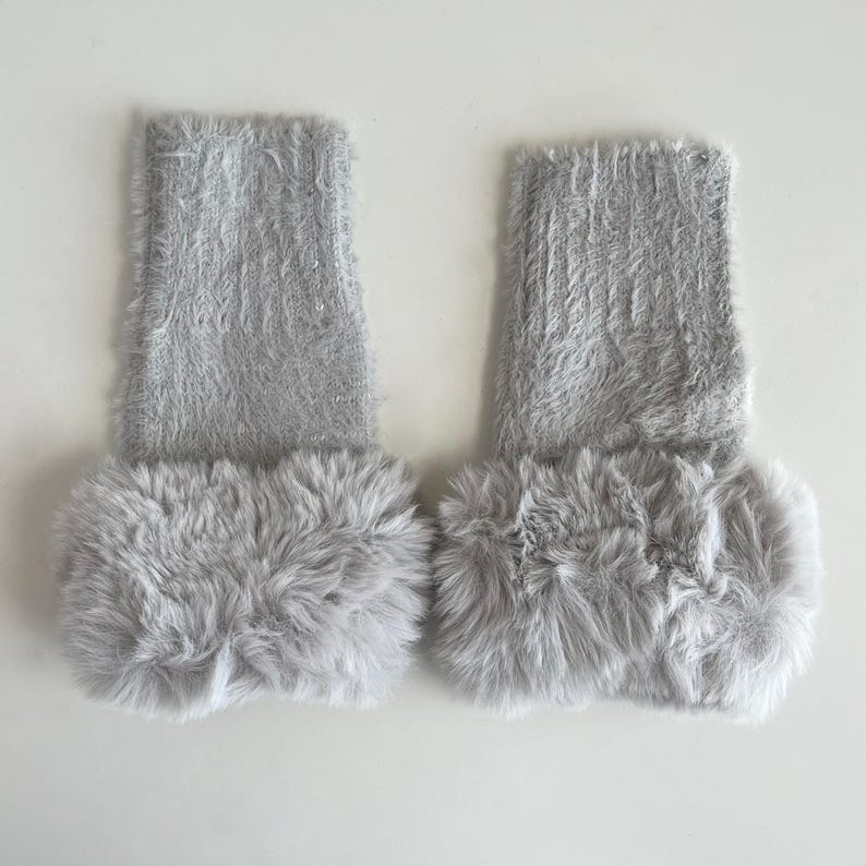 May include: A pair of gray fuzzy fingerless gloves with a fluffy white trim.