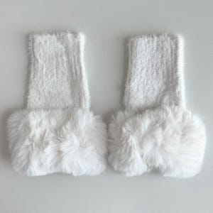 May include: A pair of white fuzzy leg warmers with a white faux fur trim.