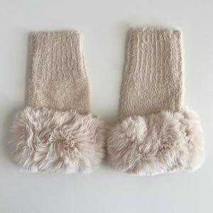 May include: A pair of beige fuzzy leg warmers with a faux fur trim.