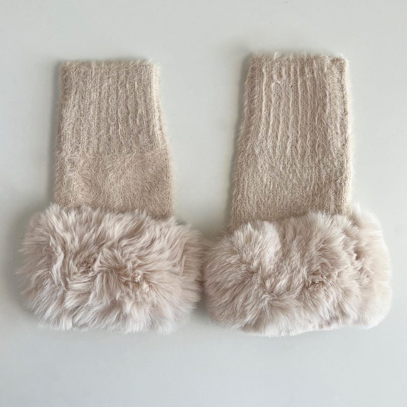 May include: A pair of beige fuzzy leg warmers with a faux fur trim.