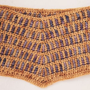 May include: Handmade crochet shorts in a warm, earthy tone with a repeating pattern of vertical stripes in shades of purple and blue. The shorts have a high-waisted design and a scalloped edge.