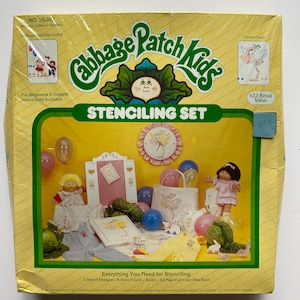 May include: A Cabbage Patch Kids stenciling set with two stencil designs, six paint colours, a brush, and a 32-page full-colour idea book. The box features a colourful illustration of Cabbage Patch Kids characters and a stork.