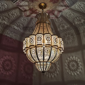 May include: A large, ornate gold chandelier with intricate cut-out designs. The chandelier has a round, bell-shaped design and hangs from a chain.