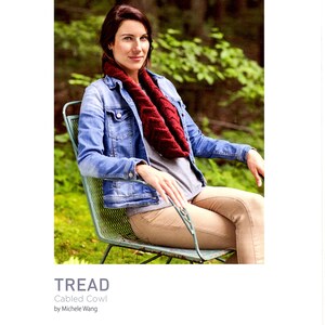 May include: A woman wearing a red cabled cowl, a blue denim jacket, and khaki pants sits on a green metal chair in a grassy area. The text "TREAD Cabled Cowl by Michele Wang" is below the image. The Brooklyn Tweed logo is below the text.