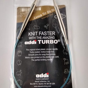 May include: A pair of 16-inch circular knitting needles in a clear plastic package. The needles are silver with blue tips and a blue cord. The package has a black background with white text that reads "KNIT FASTER WITH THE AMAZING addı TURBO®".