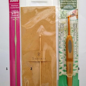 May include: Three different crochet hooks in individual packaging. The first hook is a 2.25 mm aluminum crochet hook in pink packaging. The second hook is a 2.50 mm wooden crochet hook in brown packaging. The third hook is a 2.75 mm Clover Soft Touch crochet hook in green packaging.