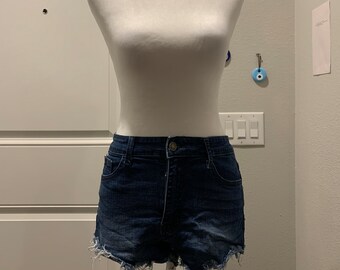 May include: A pair of dark blue denim shorts with frayed edges. The shorts are on a white mannequin.