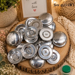 May include: A collection of shiny, silver metal buttons, size 45 (1 1/8"), are displayed on a wooden slice. The image includes a framed sign that reads "Handmade with love." An assembly tool is also shown.