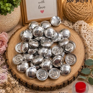 May include: A collection of shiny, silver-colored buttons, size 36 (7/8"), are displayed on a wooden slice. The image includes a sign that reads "Handmade with love." An assembly tool is also visible.