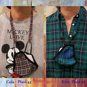 Op de afbeelding: Twee mensen dragen geruite mondmaskers aan lanyards. De persoon links draagt een grijze trui met de tekst "Mickey Love" erop gedrukt. De persoon rechts draagt een groen-zwart geruit overhemd. De tekst onder de afbeeldingen luidt "Cola - Plaid 43" en "Kirk - Plaid 68".