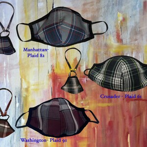 Op de afbeelding: Vier verschillende geruite mondmaskers met zwarte bies en verstelbare bandjes. De maskers zijn gelabeld "Manhattan - Plaid 82", "Crusader - Plaid 61" en "Washington - Plaid 91".