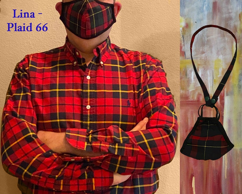 Op de afbeelding: Een rood, zwart en geel geruit overhemd met een bijpassend geruit mondkapje. Het mondkapje is bevestigd aan een zwart koord met een groene knop.