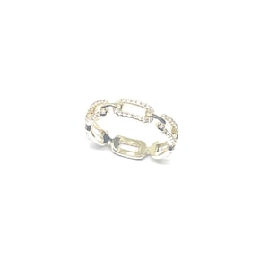 Könnte beinhalten: Goldener Kettenring mit kleinen, klaren Steinen, die in das Metall gefasst sind.