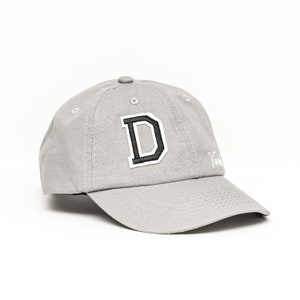 May include: A gray baseball cap with a white embroidered "D" on the front. The cap has a black brim and a white embroidered "Vanderbilt" logo on the side.