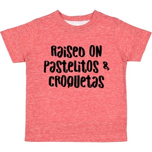 Op de afbeelding: Rood gem&ecirc;leerd T-shirt met de tekst "Raised on Pastelitos & Croquetas" in zwart.