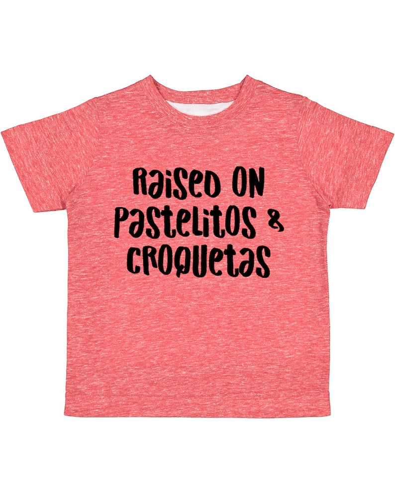 Op de afbeelding: Rood gem&ecirc;leerd T-shirt met de tekst "Raised on Pastelitos & Croquetas" in zwart.