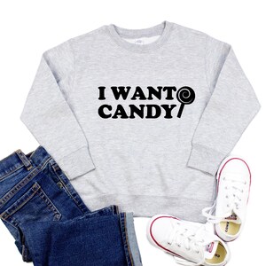 Może przedstawiać: Szara bluza z czarnym napisem "I WANT CANDY" i czarnym wzorem lizaków.