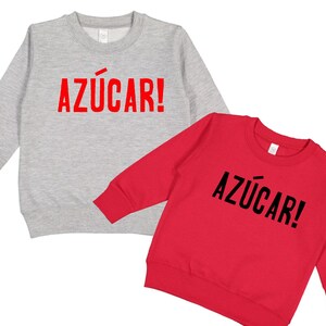 May include: Two long-sleeved sweatshirts with the word "AZ&Uacute;CAR!" printed on the front. One sweatshirt is gray and the other is red.