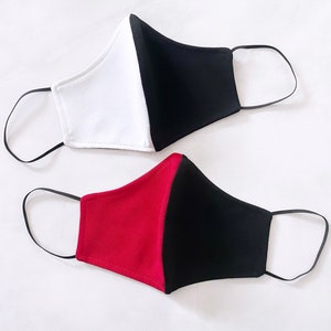 Op de afbeelding: Twee gezichtsmaskers, een wit en zwart, de andere rood en zwart.