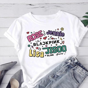 May include: White t-shirt with a colorful graphic print featuring the names "Rose", "Jennie", "Lisa", and "Jisoo" along with the text "BLACKPINK" and "BLINK forever".