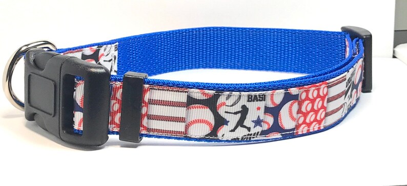 Pu&ograve; includere: Un collare per cani blu con un motivo a tema baseball con palline da baseball rosse, bianche e blu, un giocatore di baseball e la parola "BASE" su uno sfondo blu.
