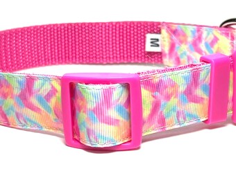 May include: A bright pink dog collar with a colorful geometric pattern in shades of yellow, blue, and pink. The collar has a plastic buckle and a metal D-ring. The size is marked with an "M" label.