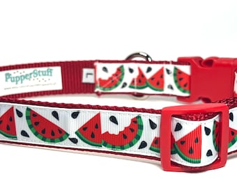 May include: Red and white dog collar with a watermelon slice pattern. The collar has a red buckle and a metal D-ring. The brand name "PupperStuff" is visible on the collar.