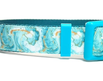 May include: A teal and white dog collar with a marbled pattern and a bright blue plastic buckle. The collar features a teal nylon webbing on the inside and is designed for pet use.