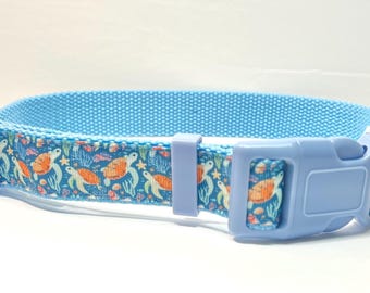 May include: A light blue dog collar with a sea turtle and coral reef pattern. The collar has a light blue plastic buckle.