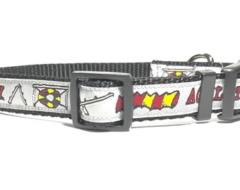 May include: Black dog collar with a white and silver ribbon featuring agility equipment and the word "Agility".