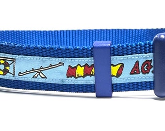 May include: Blue dog collar with a light blue stripe featuring agility equipment illustrations and the text "Agility".