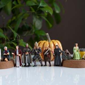 May include: A collection of miniature figurines depicting characters from the Lord of the Rings, including Gandalf, Aragorn, Legolas, and Frodo. The figurines are arranged on a table with a pumpkin in the background.