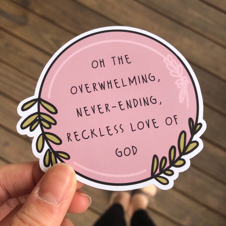 May include: Pink circle sticker with a white border and green floral accents. The sticker has the text "Oh the overwhelming, never-ending, reckless love of God" in black.