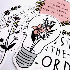 May include: A white light bulb sticker with a floral design and the text "Be the light" in black. The sticker is surrounded by other stickers with floral designs and text.
